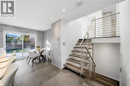 Contemporary interior featuring a modern staircase with stainless steel railings, and a dining area with sliding glass doors opening to the exterior - 2467 Bonner Road, Mississauga, ON - Indoor