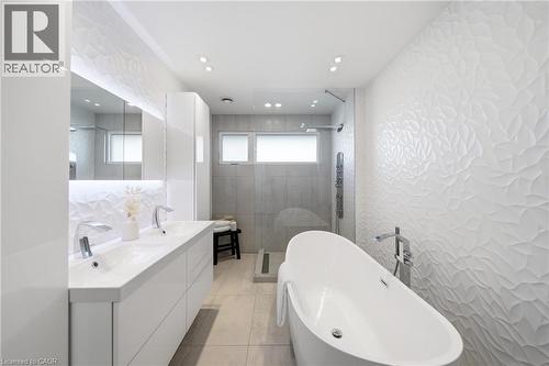 Modern bathroom featuring a freestanding bathtub, a double vanity with two sinks, a walk-in shower with a glass panel, and textured white wall tiling - 2467 Bonner Road, Mississauga, ON - Indoor Photo Showing Bathroom
