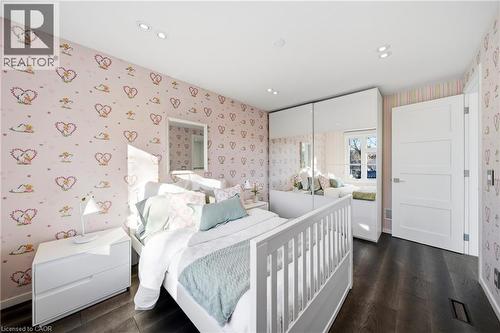 This room features dark wood flooring, white walls with patterned wallpaper, and a white interior door - 2467 Bonner Road, Mississauga, ON - Indoor Photo Showing Bedroom