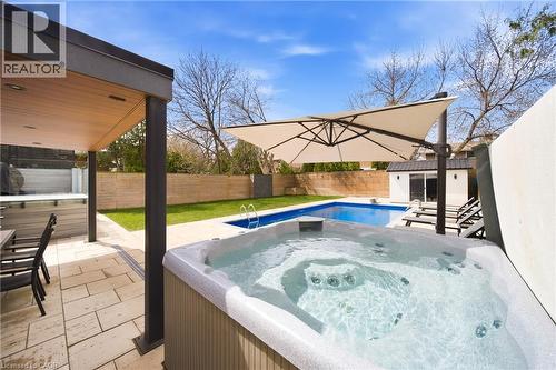 The property features a spacious backyard with a pool, a hot tub, and a covered patio area with an outdoor dining set - 2467 Bonner Road, Mississauga, ON - Outdoor With In Ground Pool