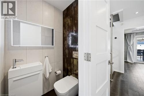 The bathroom features a modern vanity with a rectangular sink and a lighted mirror, complemented by tiled walls and a contemporary toilet - 2467 Bonner Road, Mississauga, ON - Indoor Photo Showing Bathroom