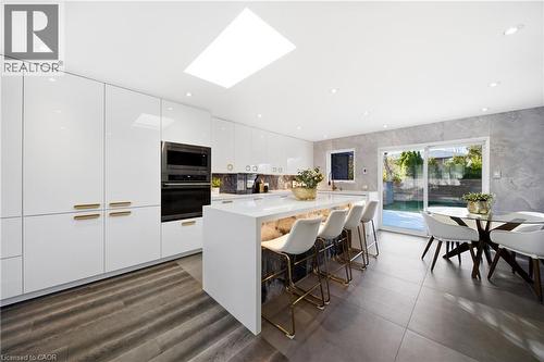 Kitchen featuring white high-gloss cabinetry, a skylight, integrated wall oven and microwave, and a kitchen island with seating - 2467 Bonner Road, Mississauga, ON - Indoor