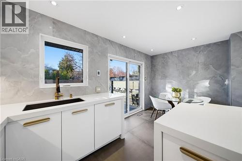 The kitchen features white cabinetry with gold-toned hardware, a black sink with a gold-toned faucet, and light-colored countertops - 2467 Bonner Road, Mississauga, ON - Indoor