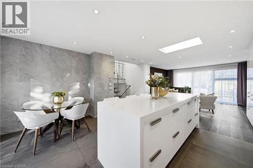 Open-concept living space featuring a spacious kitchen island with a white countertop, recessed lighting, a skylight, and large windows with sheer curtains - 2467 Bonner Road, Mississauga, ON - Indoor