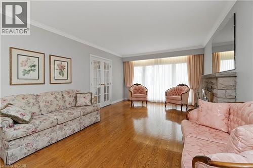Spacious living area featuring hardwood flooring, crown molding, and a stone fireplace - 36 Buckingham Drive, Hamilton, ON - Indoor Photo Showing Living Room