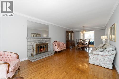 Living area featuring hardwood floors, a stone fireplace, and crown molding - 36 Buckingham Drive, Hamilton, ON - Indoor Photo Showing Living Room With Fireplace