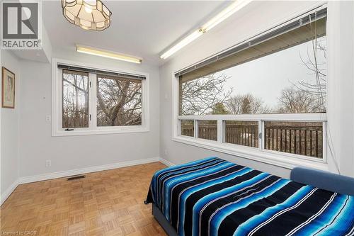 This room features parquet flooring, a large window providing ample natural light, and a second expansive window with views of trees and a wooden railing - 36 Buckingham Drive, Hamilton, ON - Indoor
