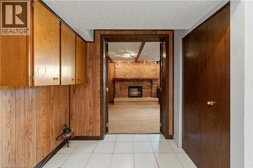 The property features wood paneling, white tiled flooring, and a doorway leading to a room with a brick fireplace - 36 Buckingham Drive, Hamilton, ON - Indoor Photo Showing Other Room