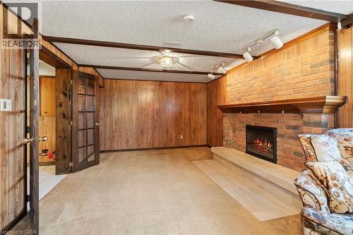 Living area featuring wood paneling, a brick fireplace with a wood mantle, and a carpeted floor - 36 Buckingham Drive, Hamilton, ON - Indoor With Fireplace
