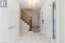 Bright entryway featuring white tiled flooring, a clear crystal chandelier, and a staircase with wooden handrails and carpeted treads - 36 Buckingham Drive, Hamilton, ON  - Indoor Photo Showing Other Room 