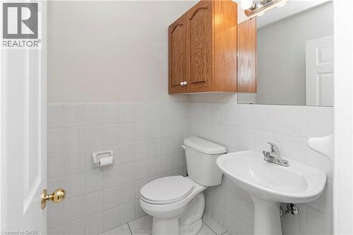 Bathroom featuring a pedestal sink, a toilet, a wooden wall cabinet, and a wall-mounted mirror with a light fixture - 36 Buckingham Drive, Hamilton, ON - Indoor Photo Showing Bathroom