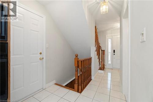 The property features a bright entrance hall with white tiled flooring, a wooden staircase, and a decorative overhead light fixture - 36 Buckingham Drive, Hamilton, ON - Indoor Photo Showing Other Room