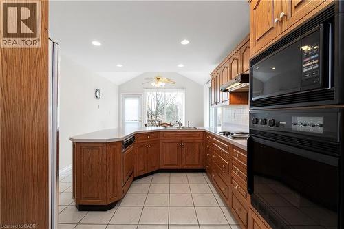 Kitchen featuring wood cabinetry, an integrated oven and microwave, tiled flooring, and a vaulted ceiling with recessed lighting - 36 Buckingham Drive, Hamilton, ON - Indoor Photo Showing Kitchen