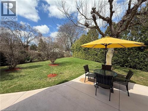 The property features an extensive lawn area with mature trees and shrubbery, along with a paved patio area - 23 Percy Court, Hamilton, ON - Outdoor