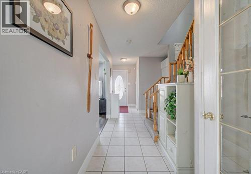 The property features a hallway with light-colored tile flooring, leading towards a front door with an oval glass insert - 334 Christopher Drive, Cambridge, ON - Indoor Photo Showing Other Room