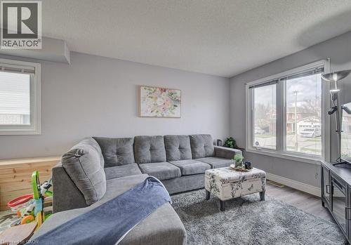 Living area featuring light grey walls, grey flooring, and large windows providing natural light - 334 Christopher Drive, Cambridge, ON - Indoor Photo Showing Living Room