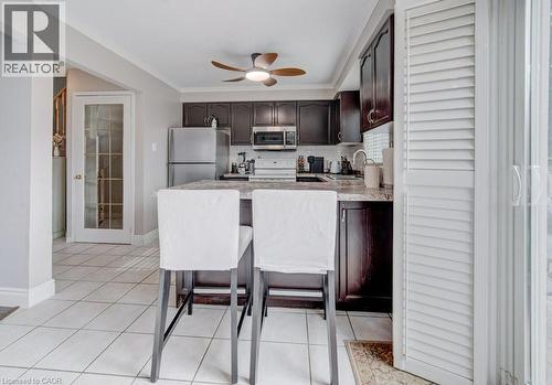 The kitchen features dark wood cabinetry, stainless steel appliances, and a central island with a granite countertop and seating - 334 Christopher Drive, Cambridge, ON - Indoor Photo Showing Kitchen