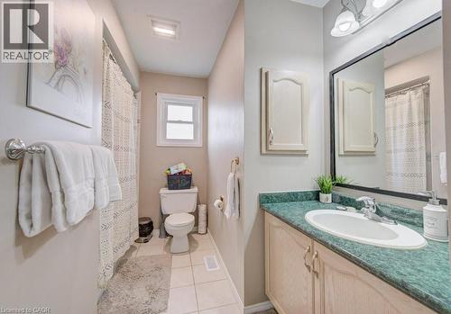The bathroom features a vanity with a green countertop and an integrated sink, a toilet, and a window - 334 Christopher Drive, Cambridge, ON - Indoor Photo Showing Bathroom