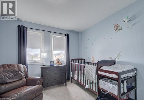 The room features light blue walls, two windows with blinds and dark curtains, and a light-colored carpet - 334 Christopher Drive, Cambridge, ON - Indoor Photo Showing Bedroom
