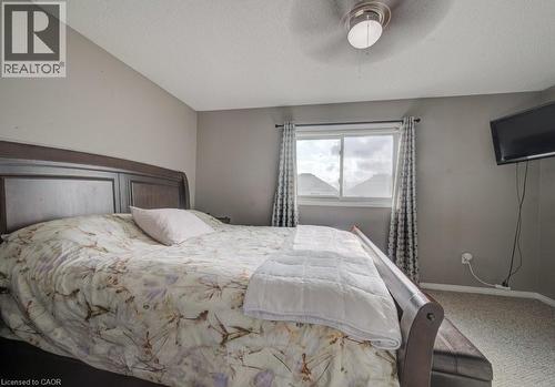 This room features a window with patterned curtains, a ceiling fan with integrated lighting, and neutral-toned carpeting - 334 Christopher Drive, Cambridge, ON - Indoor Photo Showing Bedroom