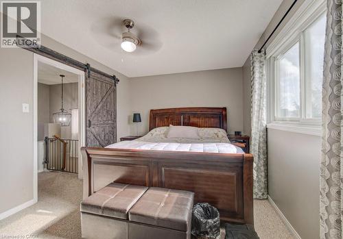 This room features light-colored carpeted flooring, a ceiling fan with integrated lighting, and a window with white trim - 334 Christopher Drive, Cambridge, ON - Indoor Photo Showing Bedroom