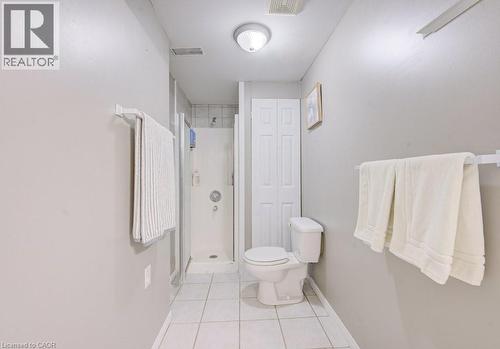 The bathroom features a shower with a clear enclosure, a toilet, and white tile flooring - 334 Christopher Drive, Cambridge, ON - Indoor Photo Showing Bathroom