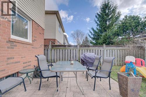 The property features a patio area with stone paving, a privacy fence, and mature trees in the background - 334 Christopher Drive, Cambridge, ON - Outdoor With Deck Patio Veranda With Exterior