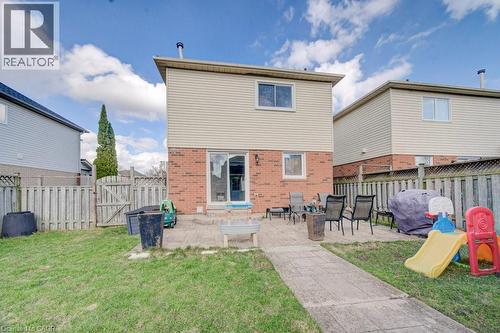 The property features a brick and siding exterior with a patio area and a grassy yard - 334 Christopher Drive, Cambridge, ON - Outdoor With Exterior