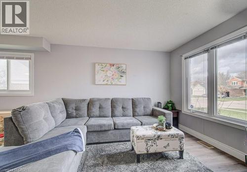 The living area features light-colored walls, large windows, and a grey sectional sofa - 334 Christopher Drive, Cambridge, ON - Indoor Photo Showing Living Room