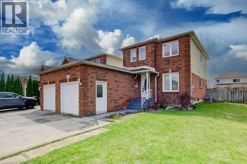 The property features a brick facade with light-colored siding, a two-car garage with white doors, and a well-maintained green lawn - 334 Christopher Drive, Cambridge, ON - Outdoor
