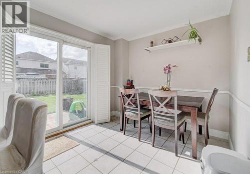 This dining area features tile flooring and a glass sliding door with white louvered shutters, providing direct access to the backyard - 334 Christopher Drive, Cambridge, ON - Indoor Photo Showing Dining Room