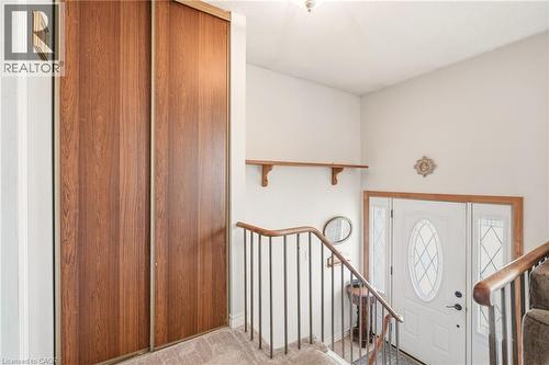 Entryway featuring a white door with decorative glass inserts, a wood-framed mirror, and a wooden railing - 2349 Middlesmoor Crescent, Burlington, ON - Indoor Photo Showing Other Room