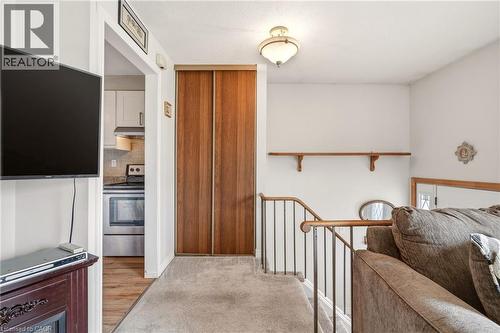 The carpeted hallway features a wooden bi-fold door, a ceiling-mounted light fixture, and a wooden handrail - 2349 Middlesmoor Crescent, Burlington, ON - Indoor Photo Showing Other Room