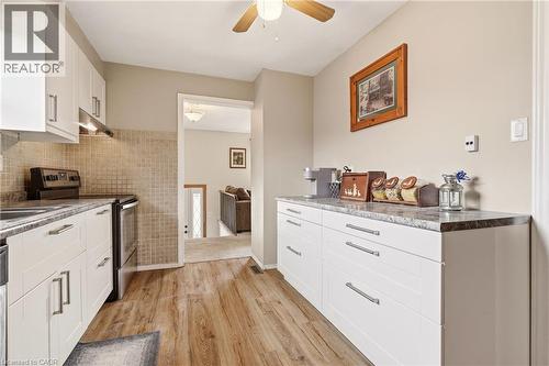 The kitchen features white cabinetry, a tiled backsplash, and wood-look flooring - 2349 Middlesmoor Crescent, Burlington, ON - Indoor Photo Showing Kitchen
