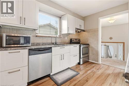 The kitchen features white cabinetry, a tiled backsplash, and stainless steel appliances including a microwave, dishwasher, and oven - 2349 Middlesmoor Crescent, Burlington, ON - Indoor Photo Showing Kitchen