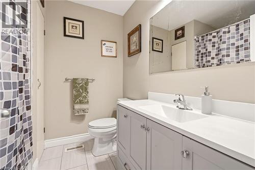 Bathroom featuring a shower with a patterned curtain, a toilet, a vanity with a white countertop and double-door storage, and light-toned tile flooring - 2349 Middlesmoor Crescent, Burlington, ON - Indoor Photo Showing Bathroom
