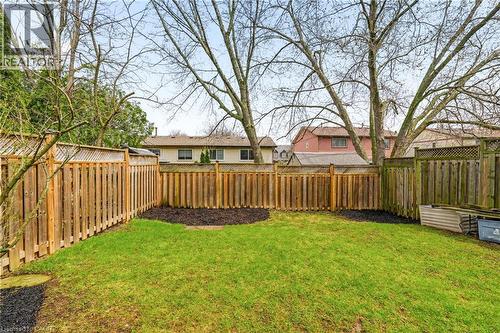 The property features an outdoor area with a well-maintained lawn, surrounded by a wooden fence - 2349 Middlesmoor Crescent, Burlington, ON - Outdoor