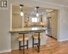 Kitchen featuring a pass-through bar with pendant lighting, granite countertops, stainless steel appliances, and wood flooring - 