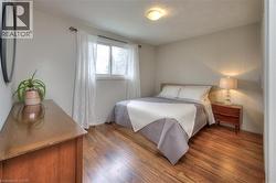 This room features warm hardwood flooring, a window with sheer curtains, and a ceiling-mounted light fixture - 