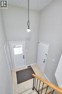 Inviting entryway featuring light-colored flooring, a white door with an upper window pane, and a decorative overhead light fixture - 