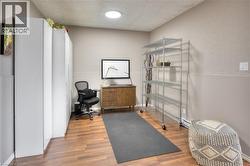 This versatile room features warm-toned flooring, neutral painted walls, and a circular ceiling light fixture - 