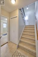 Entryway featuring light-colored tile flooring, a staircase with a dark metal railing, and a white closet door - 