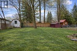 The property offers a spacious yard with a lush lawn, established trees, and a wooden fence - 