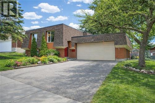 This property features a spacious paved driveway, an attached garage, and a well-maintained front garden with a variety of plantings - 42 Culpepper Drive, Waterloo, ON - Outdoor