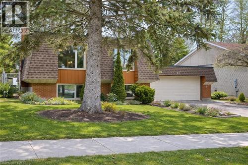 The property features a well-maintained front yard with mature trees and landscaping, a driveway, and an attached garage - 42 Culpepper Drive, Waterloo, ON - Outdoor