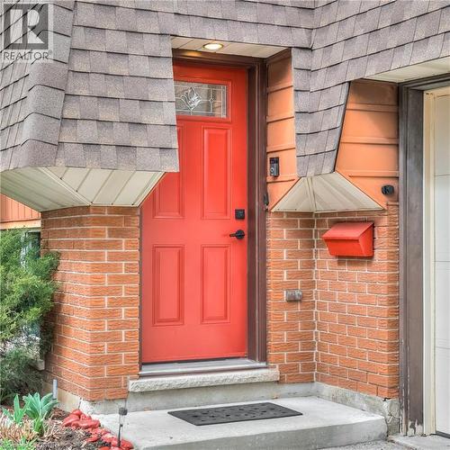 The property features a brick exterior and a vibrant red front door with a decorative glass transom - 42 Culpepper Drive, Waterloo, ON - Outdoor With Exterior
