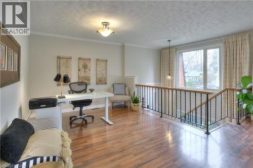 The property features wood flooring, a window offering views of the outdoors, and a staircase with a black metal railing and wooden handrail - 42 Culpepper Drive, Waterloo, ON - Indoor Photo Showing Other Room