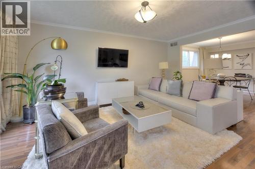 The living area features hardwood flooring, a ceiling-mounted light fixture, and crown molding - 42 Culpepper Drive, Waterloo, ON - Indoor Photo Showing Living Room
