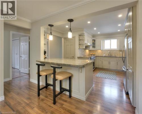 The kitchen features a breakfast bar with pendant lighting, recessed lighting, wood flooring, and light-colored cabinetry - 42 Culpepper Drive, Waterloo, ON - Indoor