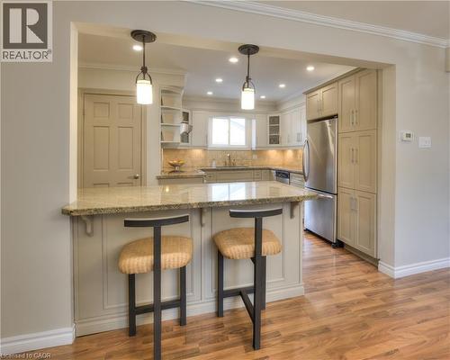 Kitchen featuring a pass-through bar with pendant lighting, granite countertops, stainless steel appliances, and wood flooring - 42 Culpepper Drive, Waterloo, ON - Indoor Photo Showing Kitchen With Upgraded Kitchen